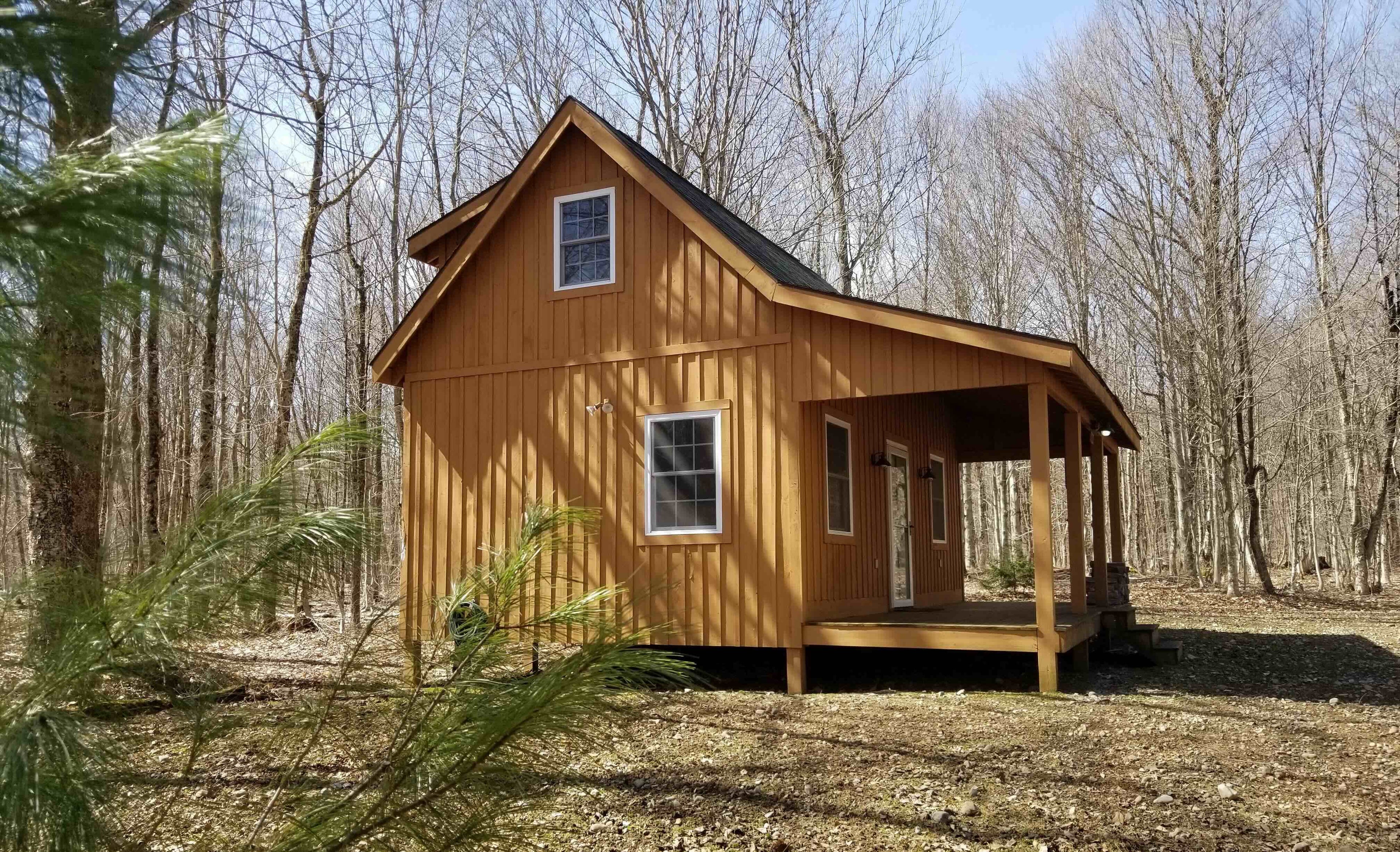 Wooden cabin in a forest setting with a covered porch.